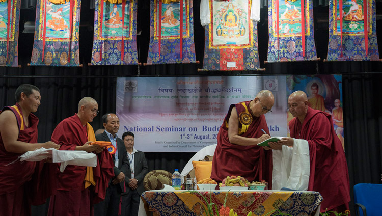 Sua Santità il Dalai Lama mentre scrive una dedica su tre libri, all’inaugurazione del seminario “Il Buddhismo in Ladakh” presso l’Istituto Centrale di Studi Buddhisti di Leh, Ladakh (India) il 1° agosto 2017. (Foto di Tenzin Choejor/OHHDL)