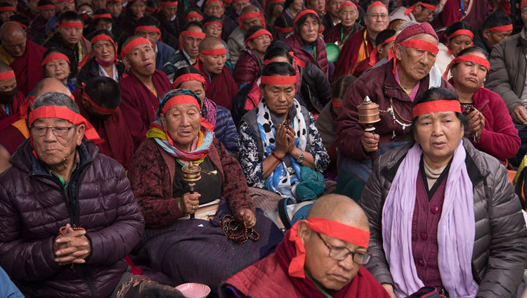 I partecipanti all’iniziazione di Avalokiteshvara indossano le bende rituali mentre ascoltano Sua Santità il Dalai Lama. Bodhgaya, Bihar, India, il 16 gennaio 2018. Foto di Manuel Bauer