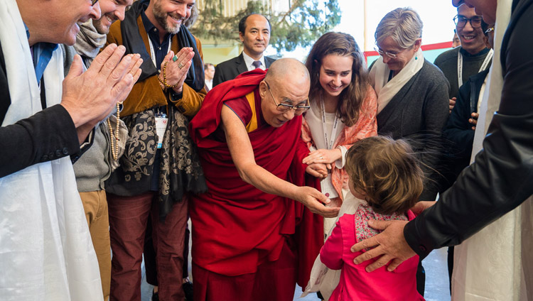 Sua Santità il Dalai Lama saluta una bambina prima di entrare nel Tempio Tibetano Principale per partecipare all'ultimo giorno della Mind & Life Conference a Dharamsala, India, 16 marzo 2018. Foto di Tenzin Choejor