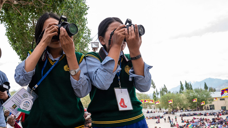 Due ragazze del TCV Photography Club scattano foto durante il discorso di Sua Santità il Dalai Lama alla Tibetan Children's Village School Choglamsar di Leh, Ladakh, India, il 1 agosto 2018. Foto di Tenzin Choejor