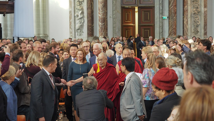 Accompagnato dalla direttrice della Nieuwe Kerk Cathelijne Broers Sua Santità il Dalai Lama saluta il pubblico al suo arrivo. Amsterdam, Paesi Bassi, il 15 settembre 2018. Foto di Jeremy Russell