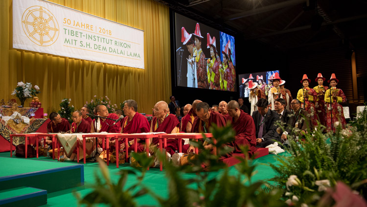 Alle spalle dei monaci, un gruppo di artisti tibetani esegue la canzone composta dall'abate Rikon Khenpo Thupten Legmon, durante la seconda giornata di celebrazioni in occasioni del cinquantenario del Tibet Institute Rikon. Winterthur, Svizzera, il 22 settembre 2018. Foto di Manuel Bauer